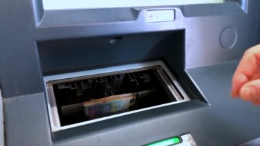Bir kişi ATM 'den Euro banknotlarını çeker ve sayar. Bir kadın banka makinesinden para çekiyor..