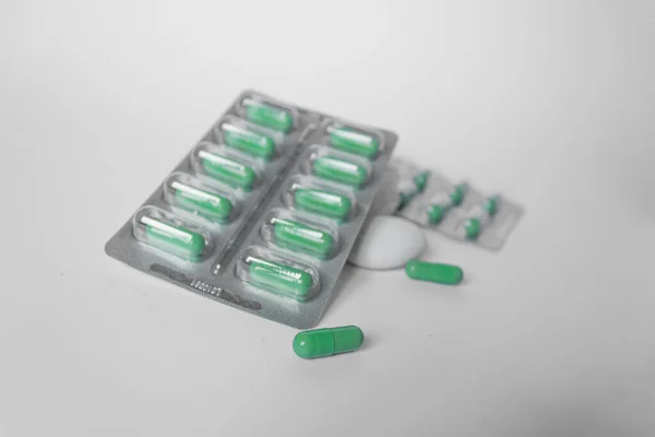 Dos ampollas de plata con suplementos y vitaminas en cápsulas verdes sobre fondo blanco. Concepto de salud. — Foto de Stock