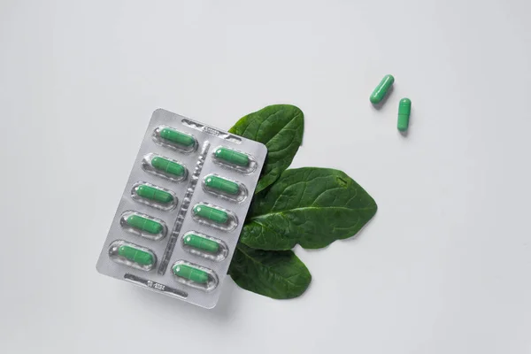 Blister de plata con suplementos dietéticos en cápsulas verdes y hojas verdes de menta. Dosis diaria. Concepto de salud. — Foto de Stock