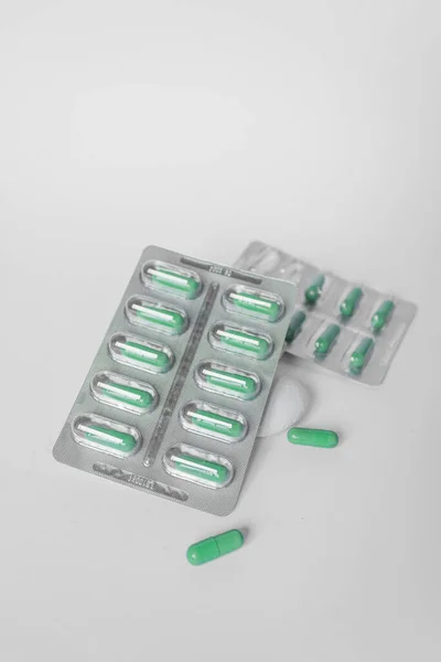 Dos ampollas de plata con suplementos y vitaminas en cápsulas verdes sobre fondo blanco. Concepto de salud. — Foto de Stock