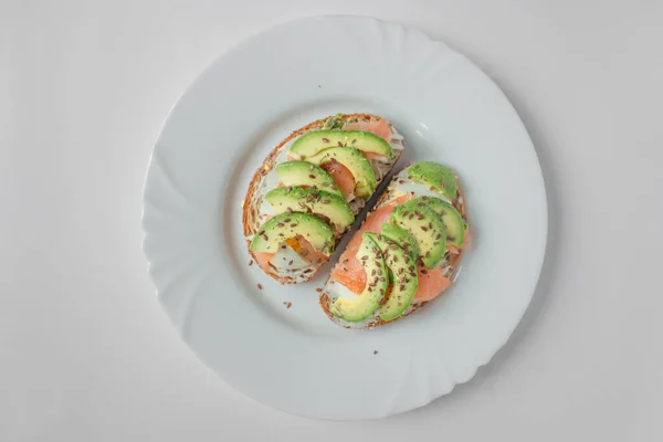 Avocado-Toast mit frischem Lachs, gekochtem Ei und Leinsamen isoliert auf weißem Teller. Gesundes Frühstück auf Low-Carb-Diät. — Stockfoto