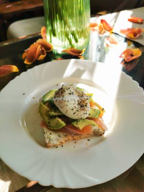 Sabah sağlıklı kahvaltı. Avokado dilimli kızarmış ekmek, haşlanmış yumurta ve beyaz tabakta soyulmuş somon balığı.. 