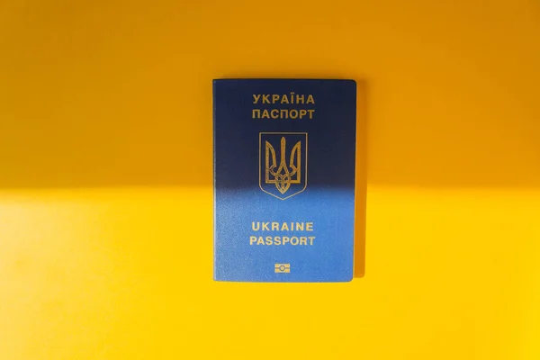 Passaporte biométrico azul Ucrânia sobre o fundo amarelo energizante. Metade à luz do sol e metade à sombra. Imigração. — Fotografia de Stock