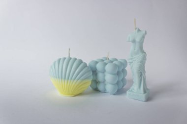 Kabarcık küpünde üç tane soya mumundan oluşan bir grup, deniz kabuğu ve Venüs formu. Mavi ve sarı pastel renklerle.