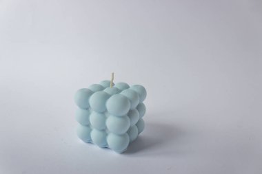 Doğal soya mumundan tek el yapımı mum. Pastel mavi renkli balon küpü şeklinde. Beyaz arkaplan.