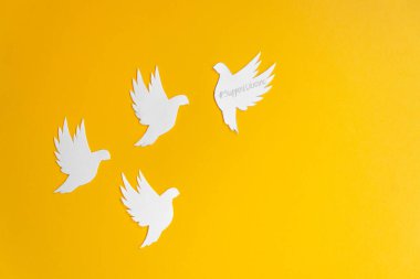 Four white paper dove birds as a symbol of peace isolated on yellow background. Peace to Ukraine. World Peace Day.