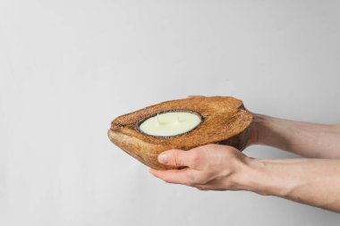 Doğal kahverengi hindistan cevizi kabuğunda organik soya mumu tutan insanlar. Beyaz arkaplanda izole.
