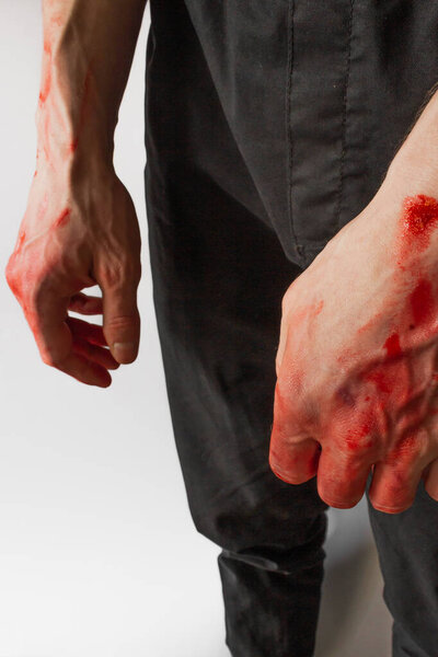 Man in black pants with bloody hands isolated on white background. Hands of a murderer and a rapist. Halloween, zombie and vampire concept. Stop war and violence in Ukraine.
