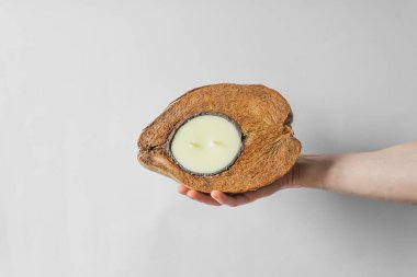 Adamın eli doğal kahverengi hindistan cevizi kabuğunda organik soya mumu tutuyor. Beyaz arka planda izole edilmiş. Sıfır atık ve çevre dostu kavram.