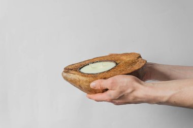 Adamın elleri doğal kahverengi hindistan cevizi kabuğunda organik soya mumu tutuyor. Beyaz arka planda izole edilmiş. Sıfır atık ve çevre dostu kavram.