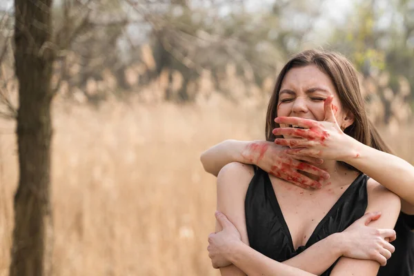 Bloody hands shutting the mouth of their victim. Portrait of young crying Ukrainian woman. Mass rape of women in Bucha. Stop war, violence and genocide in Ukraine.