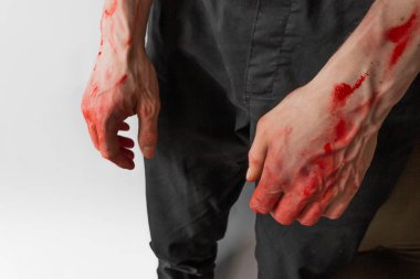 Beyaz arka planda kanlı elleri olan siyah pantolonlu bir adam. Bir katilin ve tecavüzcünün elleri. Cadılar Bayramı, zombi ve vampir kavramı. Ukrayna 'daki savaş ve şiddeti durdurun.