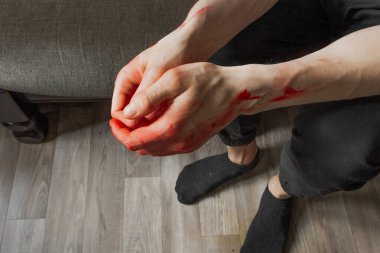 Kanlı elleri koltukta oturan siyah pantolonlu adam. Cinayetten sonra bir katilin ve tecavüzcünün elleri. Ukrayna 'daki savaş ve şiddeti durdurun.