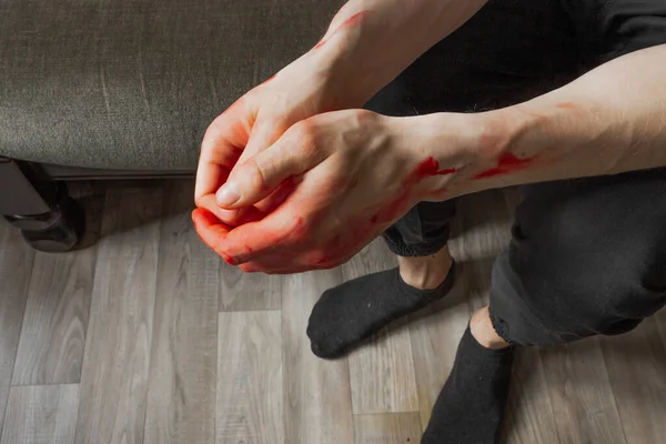 Kanlı elleri koltukta oturan siyah pantolonlu adam. Cinayetten sonra bir katilin ve tecavüzcünün elleri. Ukrayna 'daki savaş ve şiddeti durdurun.