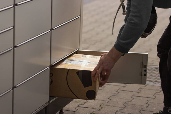  Man receives or sends a box from shopping locker in postal terminal. E-commerce shipping and delivery service. High quality photo