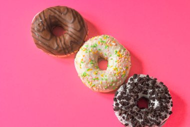 Pembe arka planda izole edilmiş renkli jöleli çörekler. Üç farklı donut seti. Düz yatıyordu. Üst Manzara. Ulusal Donut Günü konsepti.