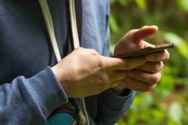 Adamın elleri akıllı telefon tutuyor. Milenyum çocuğu akıllı telefon kullanıyor, sosyal medyada sohbet ediyor, mobil servisin tadını çıkarıyor. Turist çevrimiçi haritalarda bir rota çizer. İnsanlar ve aletler. Turizm aletleri konsepti.