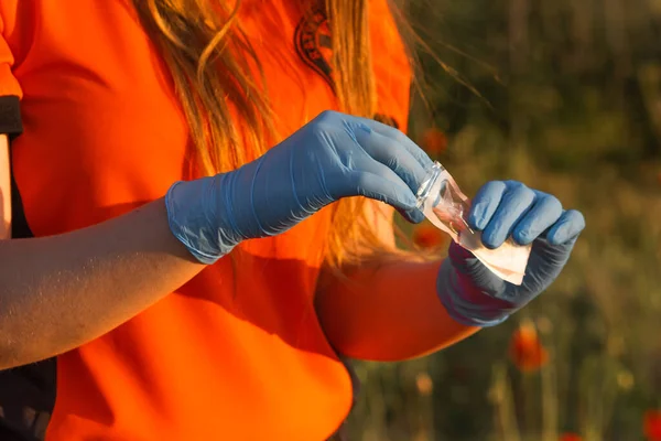 Ambulance worker in orange t-shirt and latex blue gloves take out a new syringe from a disposable package. Vaccination concept. Medicine and treatment.