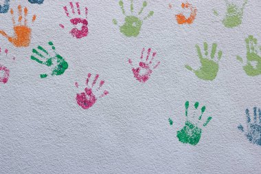 Beyaz duvarda birçok renkli el izi izole edildi. Arkadaşlık kavramı. Okul duvarında çocukların el izleri var. Çocuk Koruma Günü.