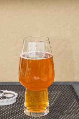 Bira fabrikasında piknik masasında köpüklü bir bardak light bira. Sarı arka planda izole edilmiş. Maya mayalı şerbetçiotu aromalı alkol içeceği. Oktoberfest kavramı.