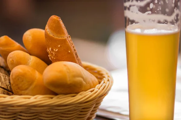 Glass of light beer and bread basket with different pastries on the wooden table at a craft czech brewery. Starter set to weekend meeting with friends. Alcoholic mans drink. Oktoberfest concept.