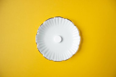 Dozlu ilaç. Sarı zemin üzerinde sadece bir yuvarlak tablet bulunan beyaz oymalı tabletin üst görüntüsü. Mesaj için yer var. Yüksek kalite fotoğraf