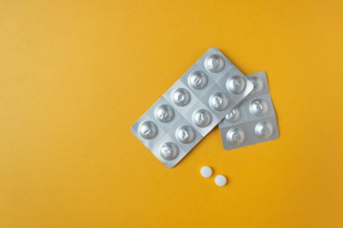 İki adet gümüş su toplayan hap ve iki adet beyaz yuvarlak tablet. Hastalığı tedavi etmek için günlük dozda ilaç. Üst Manzara. Metin için yatay fotoğraf ve boşluk.