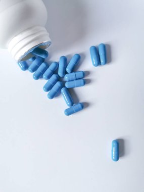 Mavi kapsüllerden oluşan bir grup şişeden dökülüyor. Uzayı metin için kopyala. Düz yatıyordu.