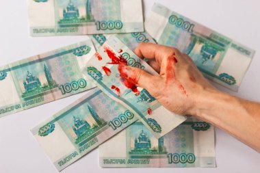 Mans hand in blood holds blood russian money, banknote face value of one thousand rubles. Bloody business with russia as a terrorist state. Concept of illegal, criminal earnings and war profiteer.