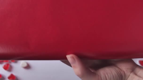 Frauenhände Halten Und Rollen Rotes Geschenkpapier Vor Dem Bildschirm Aus — Stockvideo