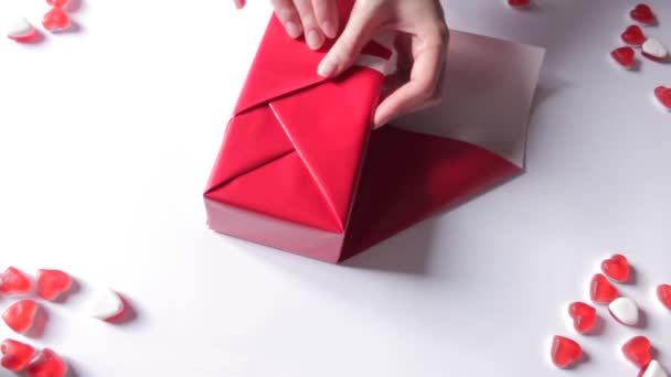 女人的手把礼品盒用红纸包起来 采用现代设计 送给她的朋友和亲戚的礼物 为假期做准备 圣诞节和情人节的概念 — 图库视频影像