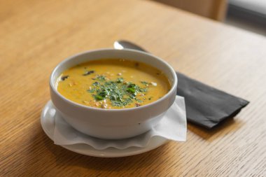 Kafedeki ahşap masada yeşil kişniş otuyla Tayland usulü köri çorbası. Geleneksel Tayland baharatlı yemekleri. Sağlıklı beslenme konsepti. Asya restoranında yemek zamanı..