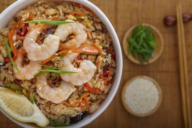 Karides, sebze ve limonlu pilav tek kullanımlık kağıt tabakta yemek çubuklarıyla bir paspasın arka planında. Asya sokak yemeği. Yukarıdan görüntüle.