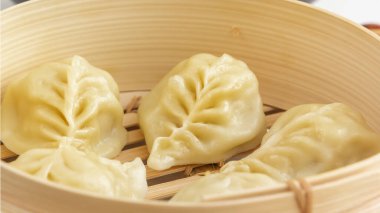 Kaynamış hamur köftesi, manti ya da hamur tatlısı. Beyaz bir masada, ahşap kazanda kıyma. Ev yapımı yemek, yakın plan.