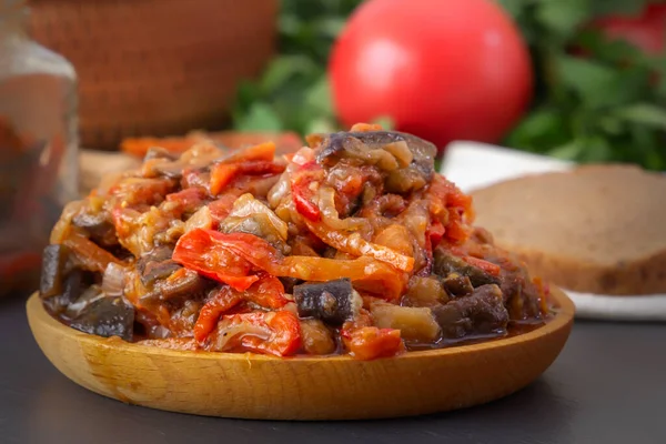 Gri bir masada, sebzeli patlıcan, domates ve yeşilliklerin arka planında. Ev yapımı. Yakın plan.