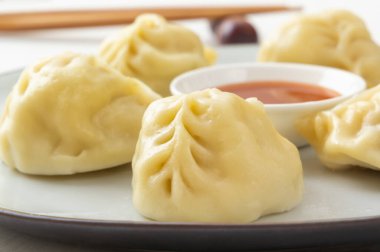 Kaynamış hamur köftesi, manti ya da hamur tatlısı, yanında yemek çubuklarıyla birlikte beyaz bir masada soslu kıyma. Ev yapımı yemek. Yukarıdan görüntüle