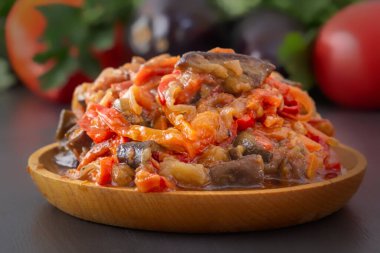 Gri bir masada, sebzeli patlıcan, domates ve yeşilliklerin arka planında. Ev yapımı. Yakın plan.