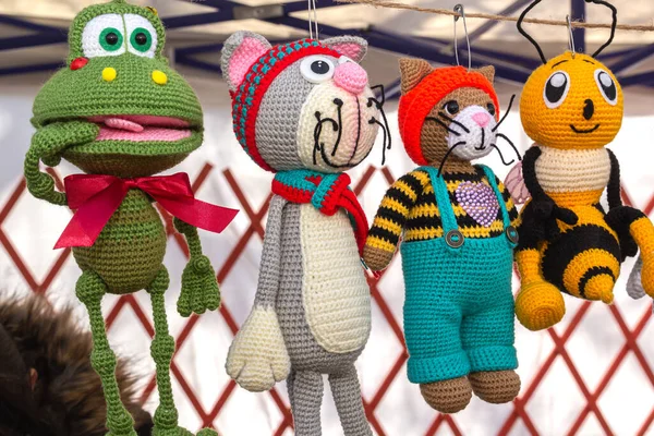 Colorful knitted handmade toys are on display for sale at a souvenir shop