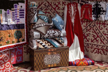 Interior decoration of a traditional nomad house yurt - a chest, pillows and blankets, felt carpets, national clothes clipart