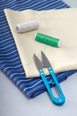 Bir kumaş parçası ve dikiş aksesuarlarıyla iplikleri kesmek için terzi makası. Yukarıdan görüntüle