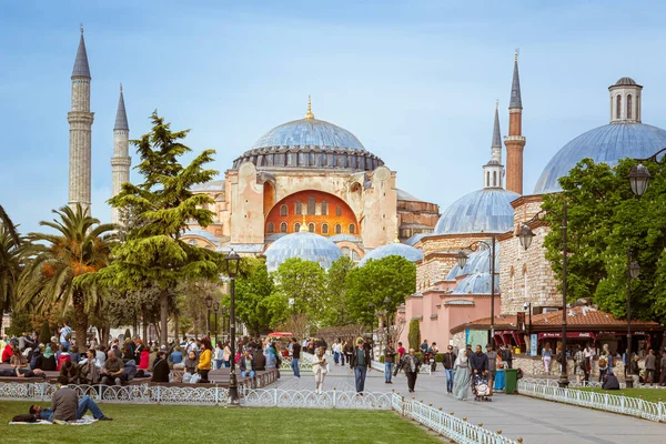 İstanbul, Türkiye - 29 Nisan 2022. Sultan Ahmet Parkı 'nda insanlar dinlenirken, arka planda Aziz Sophie Katedrali var.