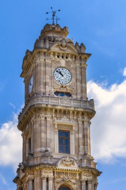 İstanbul, Türkiye - 1 Mayıs 2022. Dolmabahce Sarayı 'ndaki antik saat kulesi bulutlu mavi gökyüzüne karşı.