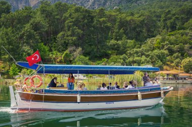Dalyan, Turkey - May 9, 2022. Tourist pleasure boat on the river against the backdrop of forested mountains