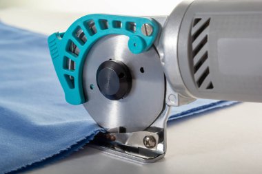 Tailor's knife cuts several layers of fabric. Close-up.