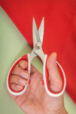 Tailor's scissors in a woman's hand are preparing to cut the fabric. Close-up