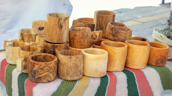 Homemade solid wood mugs are sold at a street stall on a sunny day