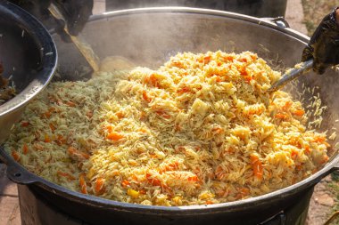 Açık ateşte büyük bir kazanda pilav pişirmek. Sokak yemeği.