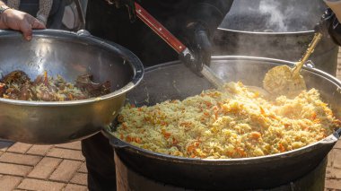 Açık ateşte büyük bir kazanda pilav pişirmek. Sokak yemeği.