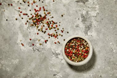 Gri desenli arka planda gri bir kasede renkli pepercorn..