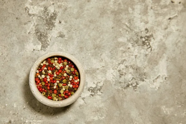 Gri desenli arka planda gri bir kasede renkli pepercorn..